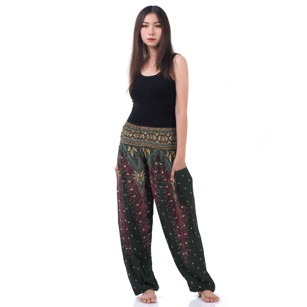Model wearing green Thai harem yoga pants with peacock print and black top, front view