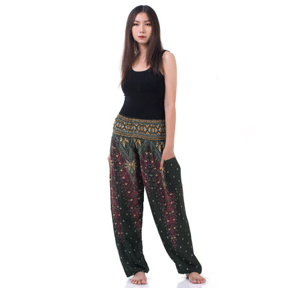 Model wearing green Thai harem yoga pants with peacock print and black top, front view