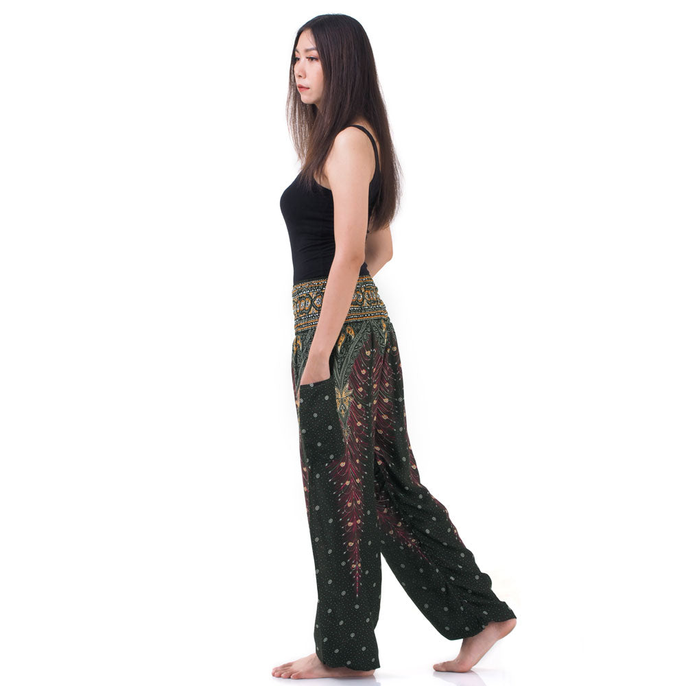 Side view of model in green Thai harem yoga pants with peacock print and black top