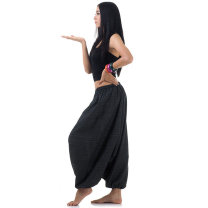 Side view of model in black women pinstripe drop crotch thai harem pants with black top