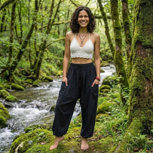 Model wearing Black Sand pinstripe harem pants in a natural forest environment with a flowing creek.
