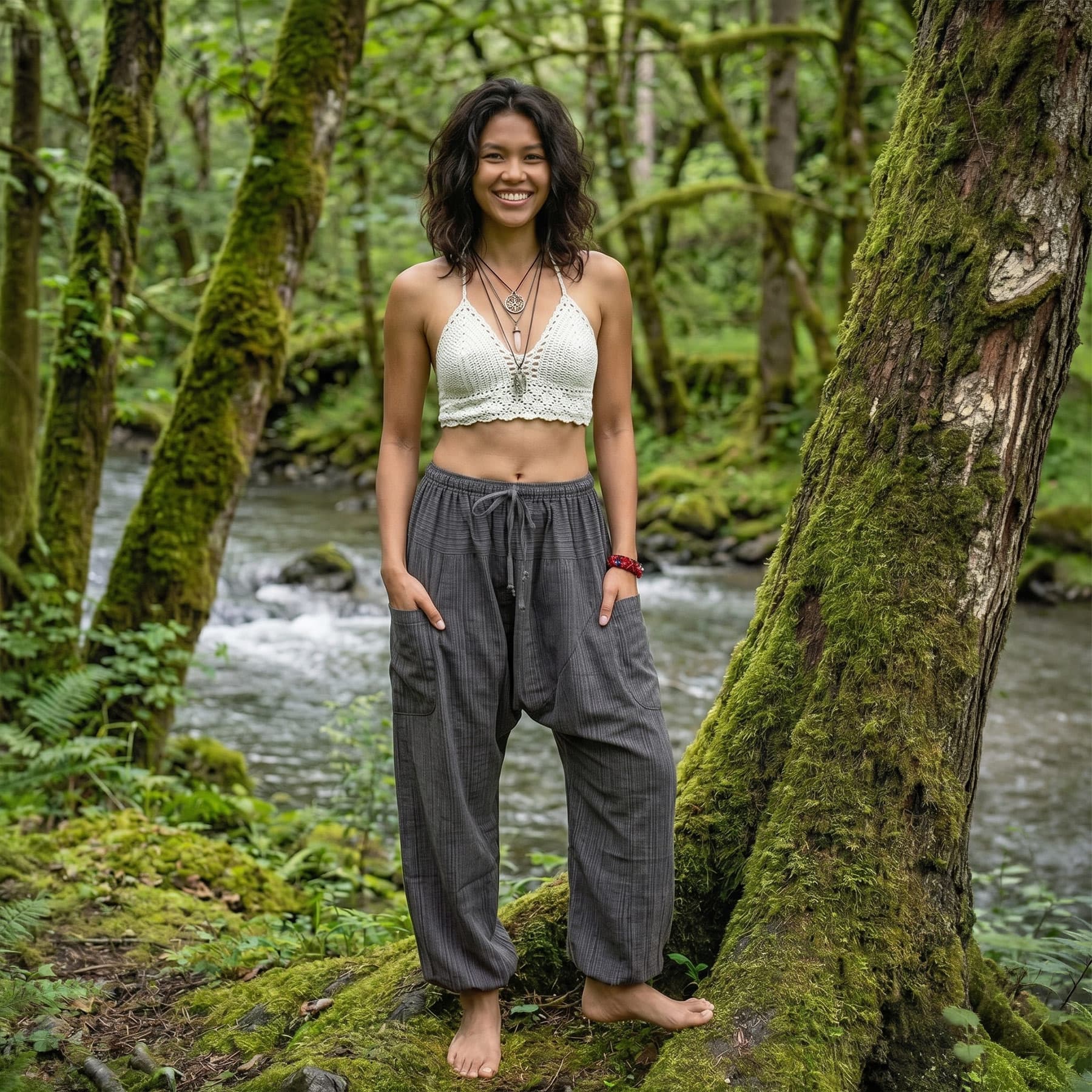Atmospheric shot of a model in Elephant Gray pinstripe harem pants by a stream in the woods.