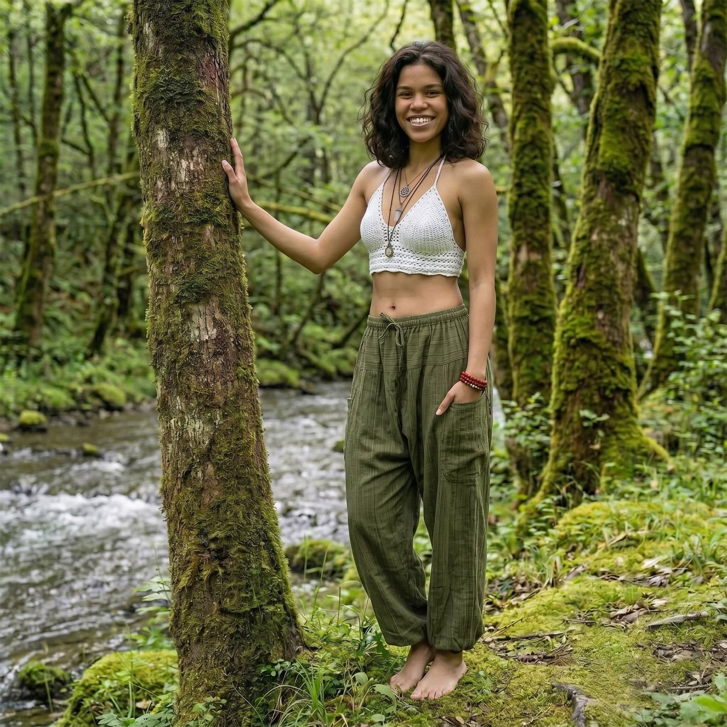 Model wearing Jungle Green pinstripe harem pants in a lush forest setting with running water.