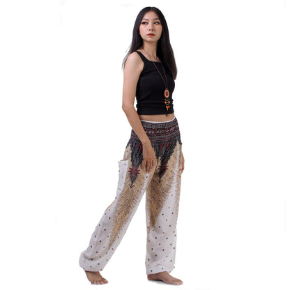 Side view of model in white Thai harem yoga pants with peacock print and black top