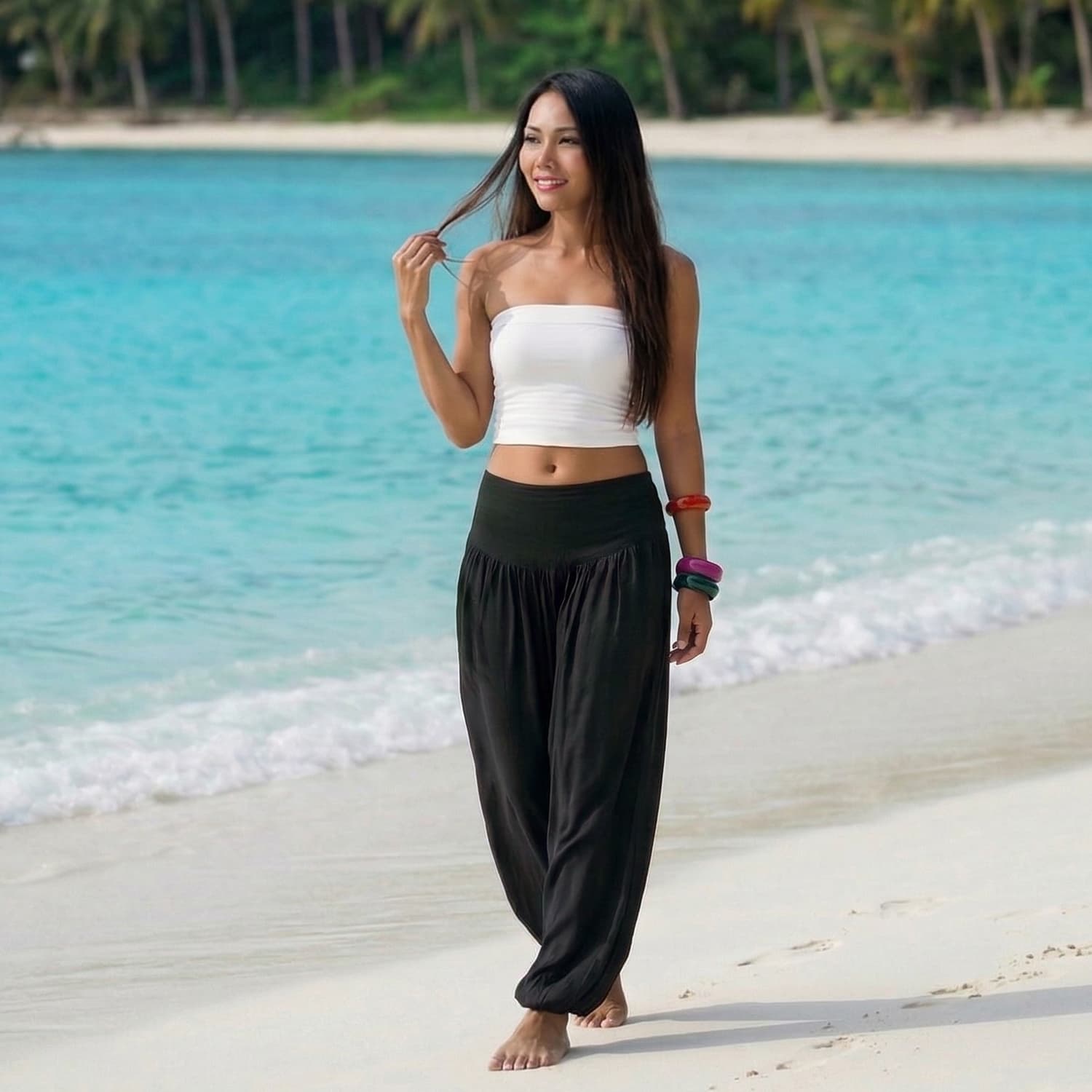 Female model in midnight black Thai harem pants walking on a Thai beach, showcasing the unique handcrafted sophistication and movement.