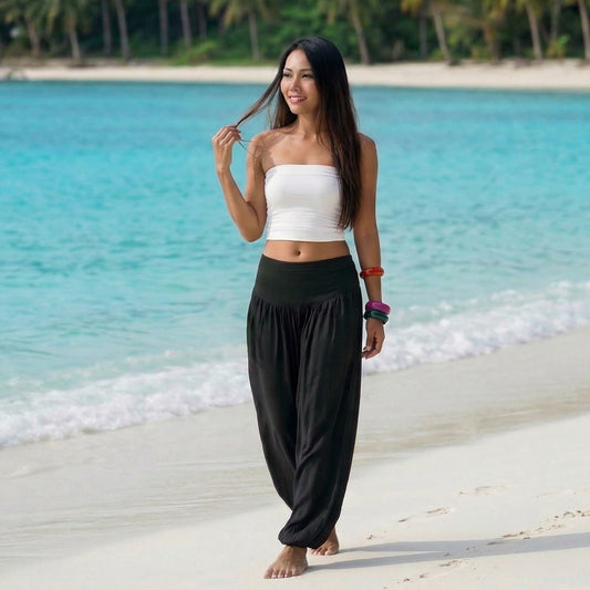 Female model in midnight black Thai harem pants walking on a Thai beach, showcasing the unique handcrafted sophistication and movement.