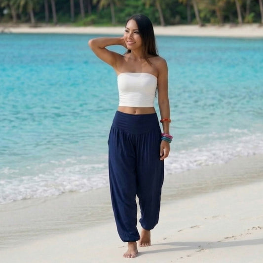 Female model in moonlight blue Thai harem pants walking on a Thai beach, showcasing the sophisticated boho style and fabric drape.