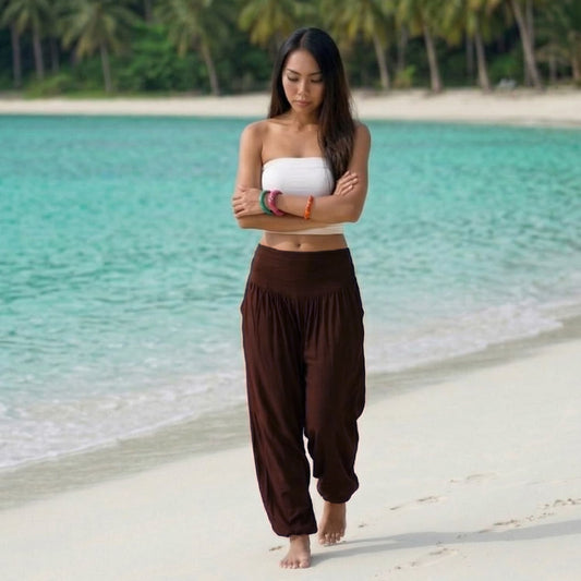 Female model in sienna serenity Thai harem pants walking on a Thai beach, demonstrating the earthy handmade color and dynamic flow.