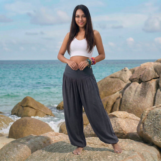 Female model in elephant gray Thai harem pants walking on a Thai beach, highlighting the classic handmade color and nature-inspired flow.
