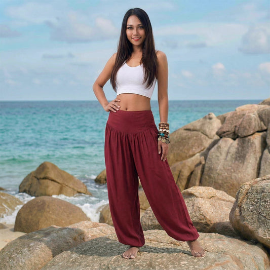 Female model in mystic maroon Thai harem pants walking on a Thai beach, demonstrating the comfortable free-moving fit S-M.