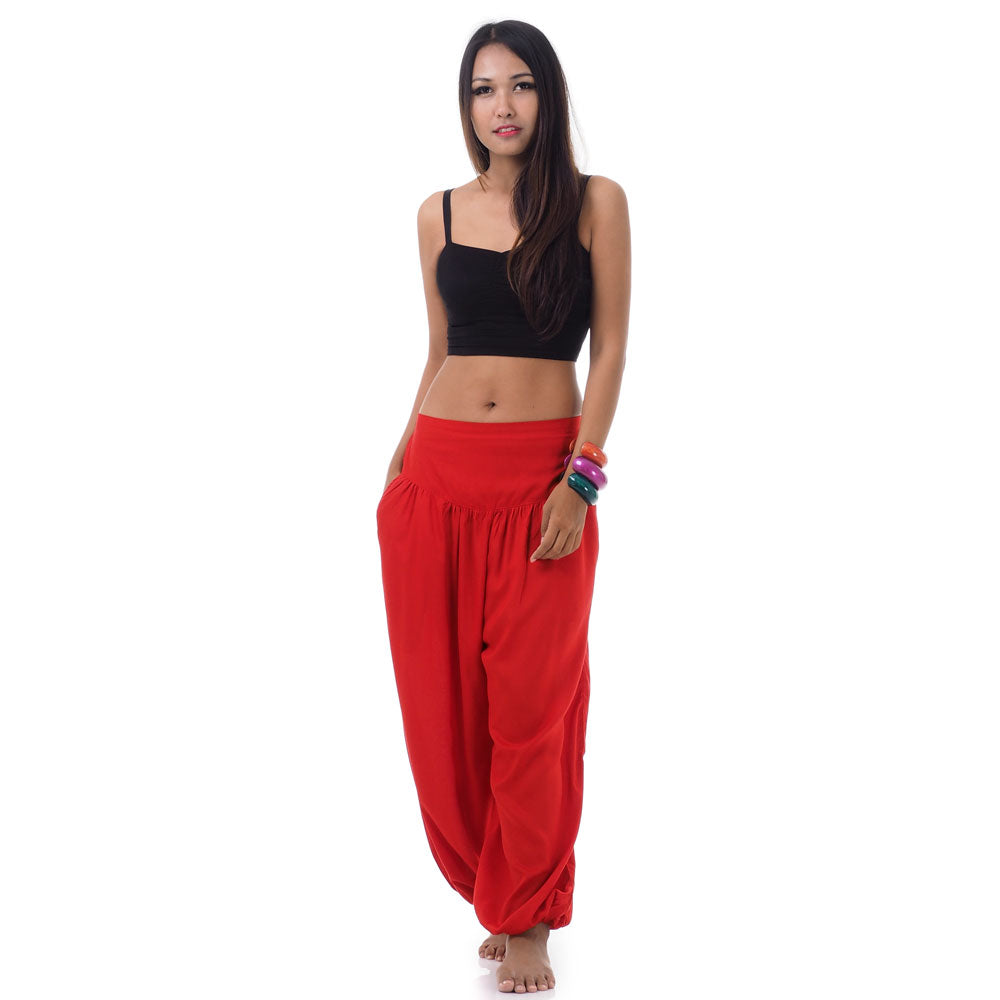 Front view of a female model wearing sunset red Thai harem pants, unique ethnic clothing.