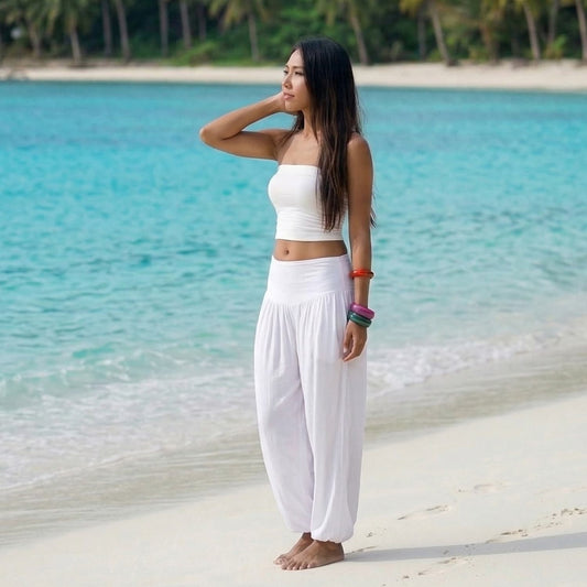 Female model in sunny white Thai harem pants walking on a Thai beach, demonstrating the exotic sophistication and flowing fabric.