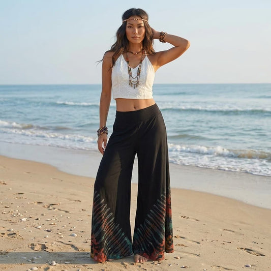 Female model standing on a sunny sandy Thai beach wearing the stylish black Midnight Magic Hippie Tie Dye Palazzo Pants.