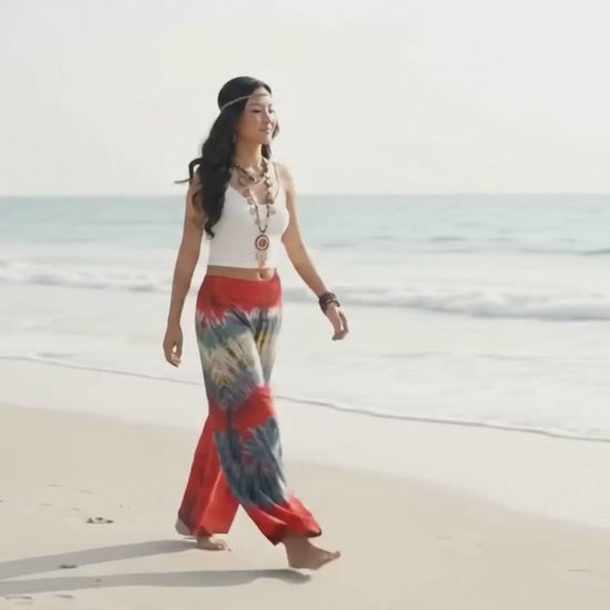 Video: Female model strolling by the sea along a sandy Thai beach wearing the relaxed Crimson Sunset Hippie Tie Dye Palazzo Pants.