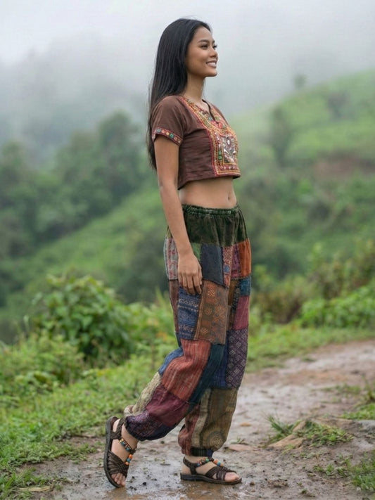 Woman wearing a patchwork my thai harem pants walking on a path with a green, misty landscape in the background